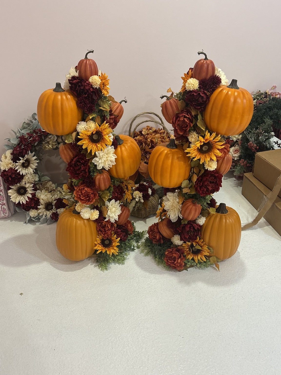 Two handmade pumpkin towers with fall flowers and patterned ribbon