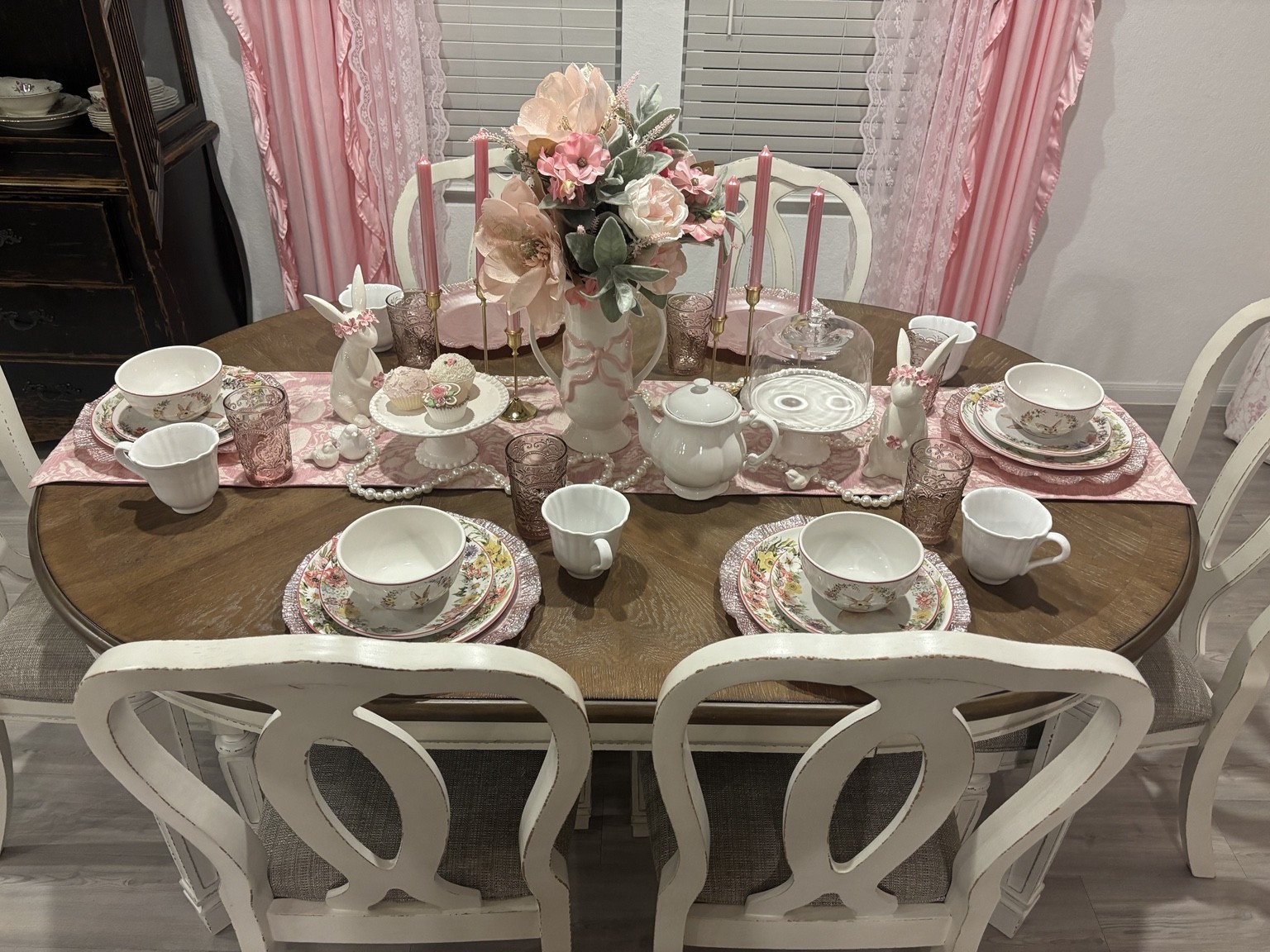 Pink floral tablescape with layered place settings and white chairs